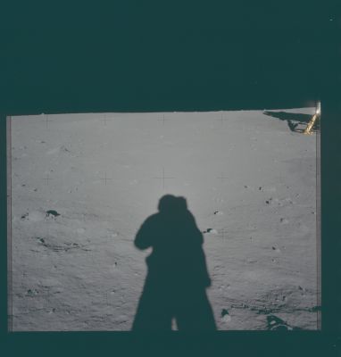 AS 11-40-5930 - Armstrong's Shadow
Caption NASA originale:"110:55:49. Neil has backed away from the LM to take a panorama. This down-Sun shows the bright halo - possibly a diffraction effect - that appeared around the shadow of Neil's helmet. Note, also, how washed out the scene is along the line of his shadow. This effect is due to the fact that, in this direction, all of the shadows - excepting only those cast by objects in the immediate foreground - are hidden by the objects that cast them. In addition there are also strong reflections off the soil particles which also contribute to the visual washout. The double crater below Neil's LM window is in the middle distance".
Parole chiave: Lunar Panorama - Apollo 11 Landing Site