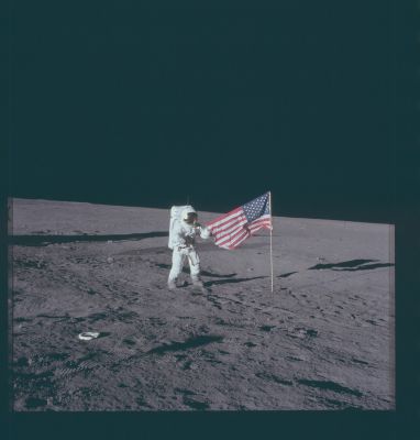 AS 12-47-6897 - Deploying the Flag
Caption NASA originale:"116:20:22 MT - Alan Bean took this picture of Pete Conrad early in the first EVA, shortly after they deployed the U.S. Flag. Note the length of Pete's shadow. The shadow of the LM enters the picture from the middle of the left edge. 
Pete is grasping the flag because the locking hinge that was supposed to hold the crossbar and flag out from the staff would not latch".
Parole chiave: Postcard from the Moon