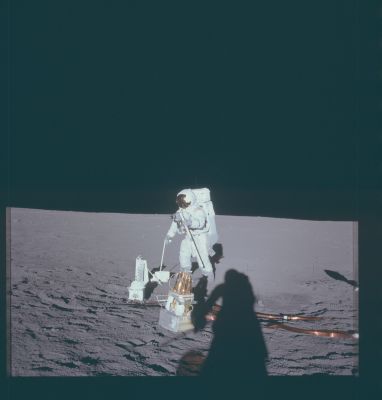 AS 12-47-6919 - Pete Conrad and Lunar Equipment
Caption NASA originale:"117:33:06 MT - Down-Sun picture showing Pete Conrad with the carrybar/antenna mast in his left hand and a Universal Handling Tool (UHT) which he is using to release the Central Station antenna gimbal assembly. 
The object in the foreground is the Magnetometer, which Alan Bean will unfold when he deploys it. Note that Conrad has laid his tongs down on the pallet. After he and Bean finish the ALSEP deployment, Pete will use the tongs to collect rocks".
Parole chiave: Lunar Surface - Astronaut & Equipment