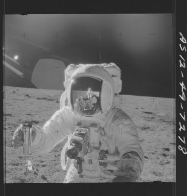 AS 12-49-7278 - Alan Bean and the "Long Can"
133:01:00 MT - This superb picture shows Al holding the so-called "Long Can", a vacuum sealed sample container more formally called the Special Environmental Sample Container (SESC). Photographer Pete Conrad has just poured soil into the can. We can see that the can is nearly full. The long-can lid is hanging by a cord from the bottom. This photo gives us a good view of the top of Al's Hasselblad camera and the cuff checklist and watch on his left sleeve. Note also that reflections of Pete and the Hand Tool Carrier are visible in Al's visor. Pete took this photo during the stop at Sharp Crater.
Parole chiave: Lunar Surface - Astronaut & Equipment