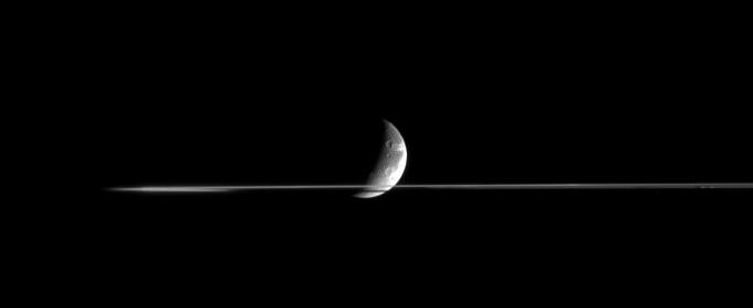 Cutting Dione...
Dione is partly occulted by Saturn's Rings in this nearly edge-on view, taken from less than 1/10th of 1° above the Ring-Plane. The side of the Rings nearer to the Cassini spacecraft was masked by Saturn's shadow at the time and appears dark. 
Bright, wispy fractures on Dione's trailing Hemisphere curl around the horizon. Sunlit terrain seen on Dione is on the moon's Saturn-facing Hemisphere. 
North is up. 

The image was taken in infrared light (centered at 752 nanometers) with the Cassini spacecraft narrow-angle camera on Nov. 3, 2005 at a distance of approximately 2.5 million kilometers (1.5 million miles) from Dione and at a Sun-Dione-spacecraft, or phase, angle of 109 degrees. Resolution in the original image was 15 kilometers (9 miles) per pixel.
Parole chiave: Saturn's Moons - Dione