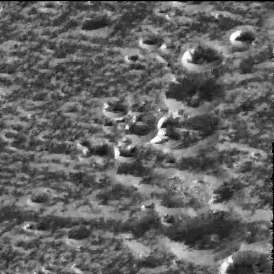 Frost on crater-tops of Ganymede
Scientists believe that water-ice frosts are the likely cause for the brightening seen around the circular rims of these craters located at a high northern latitude (57°) on Jupiter's moon Ganymede in this image taken by NASA's Galileo spacecraft on September 6, 1996. The image shows the same kind of bright, high-latitude surface areas as those first seen by the Voyager 1 spacecraft in 1979, but at higher resolution (this image spans about 18 Km - or 11 miles on a side). Even though the Sun is shining from the south, the north-facing walls of the ridges and craters are brighter than the walls facing the Sun. This is interpreted to mean that the very bright north-facing slopes are covered with surface water-ice frosts, and that these frosts preferentially accumulate in such high-latitude locations. 
Galileo scientists say that at the HR seen in Galileo images, the high-latitude brightness seen by Voyager 1 might be partly attributable to frosts forming on cooler, north-facing slopes. The right-hand side of the image is dominated by a north-south line of impact craters; the smallest ones at the top are about 2 kilometers (1.2 miles) in diameter and the large one at the bottom is about 5 kilometers (about 3 miles) in diameter. Ganymede is the largest moon in the solar system, larger than the planet Mercury and nearly the size of Mars.
Parole chiave: Jupiter Moons - Ganymede