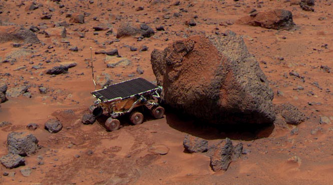Yogi and Soujourner - Sol 15
Caption NASA originale:"The Soujourner Rover is taking its Alpha Proton X-Ray Spectrometer measurement. 
It clearly shows the "two-toned" surface of this large rock. 
The nature of this color difference is not known, however. 
It might consist of wind-blown dust accumulated on the surface (the rock is leaning into the prevailing wind) or might be evidence of a break from a larger boulder as it was deposited in the ancient flood that scoured this area".
Parole chiave: Mars rocks, sand and debris