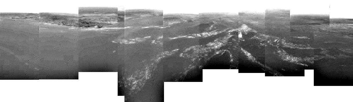 Shoreline and Drainage Channels (Mosaic)
Caption ESA originale:"This composite was produced from images returned yesterday, 14 January 2005, by ESA's Huygens probe during its successful descent to land on Titan. It shows a full 360-degree view around Huygens. The left-hand side, behind Huygens, shows a boundary between light and dark areas. The white streaks seen near this boundary could be ground 'fog' of methane or ethane vapour, as they were not immediately visible from higher altitudes. As the probe descended, it drifted over a plateau (centre of image) and was heading towards its landing site in a dark area (right). This dark area is possibly a drainage channel which might still contain liquid material. From the drift of the probe, the wind speed has been estimated at around 6-7 mt per second. These images were taken from an altitude of about 8 Km with a resolution of about 20 mt per pixel".
Parole chiave: Titan's surface