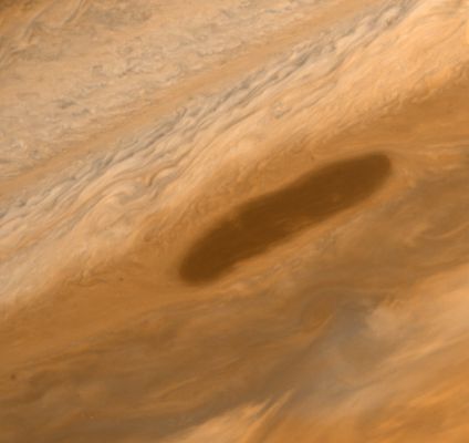 The elongated "Dark Spot" of Jupiter
Si tratta di un fenomeno anomalo il quale è stato osservato ed immortalato dalla Sonda Voyager 1, ma la cui spiegazione - in fondo - non è mai arrivata. 
Le ipotesi più accreditatate sull'argomento parlano: 

1) di una possibile "apertura" (rectius: uno "squarcio") nel tessuto compatto dell'Atmosfera Gioviana - determinato da cause ignote - tale per cui quello che vediamo NON è un sistema nuvoloso compatto e composto da nuvole più scure rispetto a quelle circostanti, bensì è un dettaglio di ciò che esiste al di sotto degli strati più esterni dell'Atmosfera Gioviana stessa;
2) di una turbolenza simile a quella (famosissima ed ultracentenaria) conosciuta come la "Macchia Rossa" di Giove ma, in questo caso, composta da nuvole "più dense" e - presumibilmente - formate da (o contenenti) elementi diversi (e più pesanti) rispetto a quelli che caratterizzano le Regioni circostanti;
3) una turbolenza Gioviana assolutamente analoga a tutte le altre, con l'unica differenza che, in questo caso, la colorazione più scura è semplicemente dovuta alle particolari condizioni di illuminazione di Giove al momento dello scatto.
Parole chiave: Jupiter's Atmosphere - upper layers