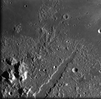The Lunar Alps
Original caption:"The European Alps were formed over millions of years by slow-moving sections of Earth’s crust pushed together, squeezing the land to form a giant arc of upthrust mountains, but the Lunar Alps were formed in an instant. It is thought that the Moon collided with a huge object, such as an asteroid, 3850 million years ago. The collision formed a huge crater, about 1000 Km in diameter. This crater was later filled with basaltic lava, forming the dark circular basin known as Mare Imbrium (Sea of Rains). After the explosive collision, fragments, rocks and dust fell back to the surface. While there is considerable debate as to the actual mechanism which formed the concentric rings, it is agreed they are not 'fallback' material. Some scientists argue that the the impact caused the lower layers to act as a liquid and that the rings then 'froze' in place. A flood of lava covered the lower inner one, but the outer one remains as a series of arc-shaped mountain ranges. 
In places these mountains rise over 3000 metres. Their inner walls are steep and well defined, but their outer slopes become more broken as elevation decreases away from the impact site. Early European astronomers named them after familiar mountain ranges, such as the Juras, the Apennines and the Alps. 

Seen in this image, Vallis Alpes (Alpine Valley) is a spectacular feature that bisects the Montes Alpes range. This valley was discovered in 1727 by Francesco Bianchini. It extends 166 kilometres from Mare Imbrium, trending north-east to the edge of the Mare Frigoris (Sea of Cold). The valley is narrow at both ends and widens to about 10 kilometres across. 

The valley floor is a flat, lava-flooded surface that has narrow sinous ‘rille’ running down the middle. It is generally considered to be a 'graben', an area between two parallel faults which has dropped below the surrounding area. This is believed to have formed after the formation of the basin, but before the full maria lava flows. The rille corresponds to a ‘lava tube’ formed in a later geological episode by high-speed and low viscosity magma. 

"SMART-1 is studying the signature of violent processes that took place during the formation of these giant impact basins, as well as the sequence of late volcanic history over the lunar surface until 3000 million years ago,” said ESA’s SMART-1 Project Scientist Bernard Foing. 

Parole chiave: The Moon from orbit - SMART-1