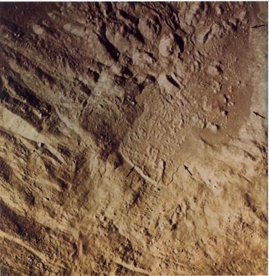 AS 14-72-9975 - The "Bright One" (detail mgnf)
When photographed with the 500-mm lens, the abundance of blocks (bright spots with shadows extending to the right) attests to the freshness of the materials on the floor of the "Bright One". Material that has flowed and in some instances formed smooth-surfaced "pools" is evident in much of the area. Arrows mark the edge of a major flow distinguished by its surface texture, color (in the original negative), location in a topographic low, and clearly defined border. Note that the abundance of boulders in the flow is much less than in nearby areas, presumably because the flow has buried most of the boulders in its path. Scientists generally agree that material has flowed here, and on the floors and flanks of many other craters, but the nature of the material that has flowed is a matter of debate.
Parole chiave: The Moon from orbit - Craters - Unnamed Crater