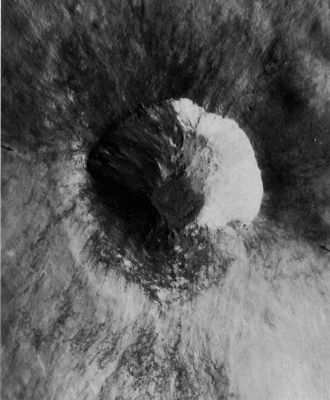 AS 15-0018 - On the rim of Gibbs Crater
Impact craters with asymmetric ray patterns and profiles can be caused by conditions other than the angle of trajectory. This 5-Km crater was formed when a meteoroid impacted on the North-East rim crest of Gibbs, a very much larger and older crater near the Moon's East limb. In this restricted view, Gibbs' rim is the dark area in the North half of the picture, and its wall is the light area in the south half. The rim crest extends from arrow to arrow. Discrete rays of both light and dark ejecta are well developed around the North half of the small crater where they were deposited on a relatively level surface. They are poorly developed around the South side of the small crater, probably having been partly destroyed by mixing as the ejected materials cascaded down the much steeper wall of the Crater Gibbs. Subsequent erosion has further destroyed the original pattern. The configuration of the small crater's rim has also been affected by topography. 
It is sharply defined along the North side but is barely discernible along the south side where large volumes of material have slumped down the wall of the older crater.
Parole chiave: The Moon from orbit - Craters - Unnamed Crater