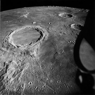 AS 15-1541 - Archimedes and Aristillus
The ejecta blanket and secondary impact craters of the mare-filled crater Archimedes (80 Km in diameter) are visible on the terrain toward the viewer (South) but not on the mare surface to the crater's left and right. Yet at one time ejecta like that to the south must have completely surrounded Archimedes because similar ejecta surrounds craters such as Aristillus (upper right). Thus, the mare lavas, in addition to filling the interior of Archimedes, obviously have covered the eastern and western parts of the ejecta. In turn, ejecta from Archimedes has covered materials of the Imbrium Basin like the rugged hills in the lower left of the picture. These stratigraphic relations prove that time elapsed between formation of the Imbrium basin and its filling by mare-time enough for impacts to create Archimedes, the deeply flooded crater to its right (arrow), and similar "Imbrian-age" craters elsewhere, as was pointed out by Eugene Shoemaker in 1962.

Archimedes has no visible central peak complex. Presumably the complex exists but has been completely inundated by the mare.
Parole chiave: The Moon from orbit - Craters - Archimedes