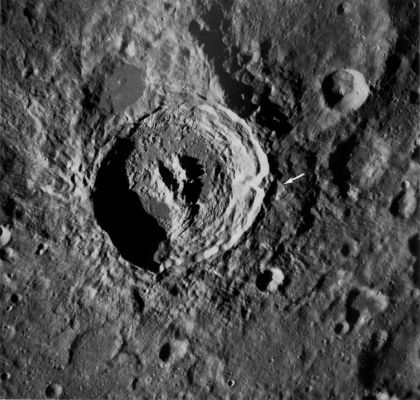 AS 16-122-19580 - King Crater
This vertical view of the crater King on the Lunar Far-Side was taken with the Apollo 16 Hasselblad camera. King, approx. 75 Km in diameter and 4 Km deep, is one of the most interesting features on the Far-Side. It is a superb example of a youthful, large crater. It attracted much attention and was the object of numerous scientific studies (Young, Brennan and Wolfe, 1972). 
King is the freshest crater on the Far-Side in its size range. Among its many interesting features are:
1) a unique lobster-claw-like central peak; 
2) a flat poollike area of dark material on the North rim believed to have once been molten; 
3) a very-well-developed field of fine ejecta extending outward for approx. two crater diameters, and 
4) a massive landslide on the South-East rim (see arrow). 

In this view the Southern part of the central peak has a distinctly ropey appearance and is segmented parallel to the terraces of the adjacent crater wall. The low Sun illumination enhances the fine texture of King's ejecta. Northeast of King the ejecta mantles an old large crater and in the southwest corner of the picture it mantles a relatively smooth terra unit. The slightly raised plateau on which the crater is situated may be part of the ring of an old basin.
Parole chiave: The Moon from orbit - Craters - King