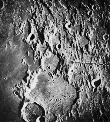 AS 16-1973 - The "Davy Crater Chain"
The Davy Crater Chain (arrow) is one of the most spectacular chains of craters on the Moon. It extends for about 50 Km across the floor of the large, very old crater Davy "Y" and onto its eastern rim. The chain may be related in origin to the pair of irregular craters Davy "G" and Davy "GA", 75 Km from the furthest end of the chain. 
Two origins have been proposed: some lunar geologists believe it is a chain of secondary impact craters and others believe it is a line of volcanic craters. The simple geometry of the Davy Chain, the symmetry and uniform spacing of its individual craters and its alinement with Davy "G", strongly support, in my opinion, a volcanic origin. Also arguing against a secondary impact origin is the fact that the Davy Chain is a lone feature. There are no other similar chains with this trend in the area. Secondary crater chains tend to occur in large numbers within the belt of secondary craters surrounding a large primary crater.

On Earth some rocks from deep within the crust have been brought to the surface through volcanic orifices, thus providing a means of studying material that would otherwise be inaccessible. For this reason the Davy area was once seriously considered as a landing site. However, when the originally planned number of Apollo missions was reduced, the Davy area was one of those eliminated.
Parole chiave: The Moon from orbit - Crater Chain