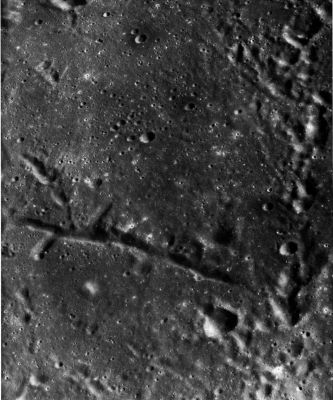 AS 16-4530 - Seconday impact craters, faults and rifles
Linear features of external and internal origin are contrasted in this area of Southernmost Mare Tranquillitatis. 
The North-trending line of overlapping, very irregular craters along the East edge of the picture is clearly a chain of secondary impact craters. Its trend is radial to Theophilus, a large crater of early Copernican age that lies about 105 Km south of this area. The flaring shapes of some of the craters and their state of preservation also suggest that Theophilus is the primary crater. The narrow, straight rifle or graben that extends westward across the picture is clearly of internal origin. It formed when tensional forces ruptured the crust, causing the floor of the rifle to subside along faults. 
Straight rifles are commonly the sites of volcanic cones or of blankets of volcanic ejecta; however, there are no signs of volcanism here that can be related to this rifle.
Parole chiave: The Moon from orbit - Chaos Terrain