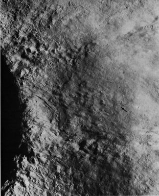 AS 16-4136 - Cratered Region near Mandel'shtam (2)
This enlarged view of part of frame AS 16-4136 shows some of the smooth flows that originate near the crest of the crater rim at the left side of photograph. Arrows point to the lower ends of two flows. 
The origin of the flow material is controversial. 
It was probably molten material generated by shock-wave compression of lunar rocks and ejected at relatively low velocities during the late stages of the formation of the impact crater; or it may have resulted from the flow of rock debris mixed with a fluidizing agent such as gas or water; or it may have been volcanically generated lava.
Parole chiave: The Moon from orbit - Highly Cratered Region