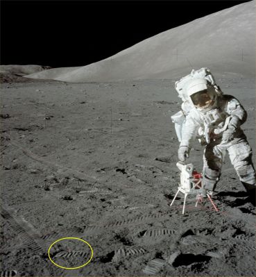 AS 17-134-20438 - Red Cable? (HR)
Caption NASA originale:"123:06:24 MT - SEP site. This frame from Gene's SEP partial pan shows Jack (Schmitt) reaching down to open the Solar Panels on the SEP Transmitter. Because of the stiffness of the suit, Jack can only reach this low by putting his right leg back and leaning to the side".

Con questo frame segnalatoci dal Dr Barca, finalmente risolviamo (molto probabilmente) una piccola querelle sulla natura dell'oggetto rosso che è stato cerchiato. Come ovvio, non possiamo essere totalmente certi che la nostra idea corrisponda a verità, ma il dettaglio in questione potrebbe essere sia uno spezzone del cavo di alimentazione del SEP Transmitter, sia una porzione del medesimo rimasta semi-interrata. 
In appoggio a questa teoria esplicativa, ci sono il colore e l'apparenza del dettaglio superficiale; in contrasto, invece, c'è la posizione del dettaglio in oggetto la quale è totalmente incoerente con la direzione principale di scorrimento del cavo (portate il frame sino al full-size e poi verificate Voi stessi). Che dire di più? La ricerca effettuata dal Dr Barca è eccellente, ma la certezza assoluta sull'effettiva natura di tantissimi dettagli della superficie della Luna (come questo), visto il silenzio della NASA, è (al momento) irraggiungibile.
Parole chiave: Lunar Equipment