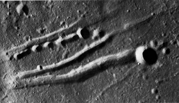 AS 17-2321 - Crater Chain
This crater chain in Southern Mare Serenitatis is clearly of internal origin because it is lined up parallel to several fault valleys or grabens. 
The craters in the chain do not appear to have any rims; consequently, they may have formed by collapse and not by the explosive ejection of volcanic material. 
The large crater in the right side of this scene, however, has a rim and so cannot be the result of collapse alone. 
The finely lineated texture across the left side of the photograph is caused by ejecta from the crater Dawes to the south.
Parole chiave: The Moon from orbit - Crater Chain