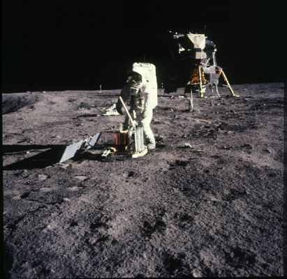 AS 11-40-5947 - Buzz at work
111:06:20 MT - Buzz may still be trying to get the seismometer leveled. As he tells Houston, the westside solar array "deployed automatically". He has not yet deployed the eastside solar array. Note the baton-like transmitting antenna and the three-pronged (cricket wicket) gnomon on the top of the main package. There are two release pins on the ground about 1 - 2 meters to the right of Buzz's feet and other pieces of discarded hardware nearby. Note the closed configuration of the SEQ Bay doors on the LM descent stage. The 'Gold' camera is between Buzz and the spacecraft.
Parole chiave: Lunar Surface - Astronaut at work