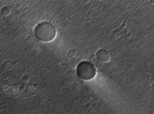 Signs of the wind in Chryse Planitia (Original NASA/MGS/MSSS b/w Frame)
Caption NASA originale:"This MGS-MOC image shows two Unnamed Impact Craters of nearly equal size, plus their associated Windstreaks. These occur in far Eastern Chryse Planitia. The Wind streaks point toward the South-West, indicating that the responsible Winds blew from the North-East. One of the two craters is shallower than the other and has a suite of large, windblown Ripples on its Floor. The shallower Unnamed Crater with the Ripples is probably older than the other, deeper Unnamed Crater".  

Location near: 20,6° North Lat. and 30,1° West Long.
Image width: ~3 Km (~1,9 mi)  
Illumination from: lower left  
Season: Northern Winter
Parole chiave: Mars from orbit - Craters - Unnamed Craters - Chrise Planitia Region