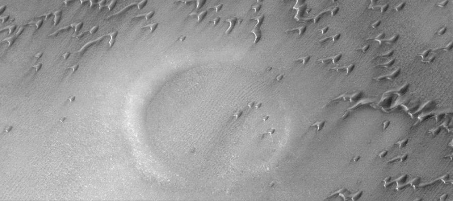 Under the Sand (Original NASA/MGS/MSSS b/w Frame)
Caption NASA originale:"This MGS-MOC image shows a partially-buried crater in the North Polar Region of Mars. 
The circular feature is surrounded and partly overlain by some of the many, many sand dunes in the area. The steepest slopes on each dune — their "slip faces" — face toward the SouthEast, indicating that the dominant winds responsible for sand transport in this Region come from the NorthWest".

Location near: 76,0° North; 82,2° West
Image width: ~3 Km (~1,9 mi)  
Illumination from: lower left  
Season: Northern Spring
Parole chiave: Mars from orbit - North Polar Features - buried crater