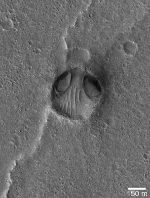 Unnamed Crater in Chrise Planitia (Original NASA/MGS/MSSS b/w Frame)
Caption NASA originale:"This MGS-MOC image shows an impact crater in Chryse Planitia, not too far from the Viking 1 Lander site, that seems to resemble a bug-eyed head. The 2 odd depressions at the north end of the crater (the "eyes") may have formed by wind or water erosion. This Region has been modified by both processes, with water action occurring in the distant past via floods that poured across western Chryse Planitia from Maja Valles, and wind action common occurrence in more recent history. This crater is located near 22.5°N, 47.9°W". Che dire? Forse gli Alieni (diremmo che in questo caso potrebbe trattarsi dei "Grigi"...) non solo posseggono "tecnologia e senso artistico" ma anche un cospicuo "senso dell'umorismo": solo così, infatti, potremmo spiegare un simile "autoritratto"! 
Scherzi a parte, in questo MGS frame è ripresa un'opera della Natura davvero incredibile e che, sicuramente, qualcuno interpreterà alla stregua della "Sfinge di Cydonia". 
Naturale o Artificiale? That is the question...
Parole chiave: Mars from orbit - Craters - Unnamed Crater - Chrise Planitia