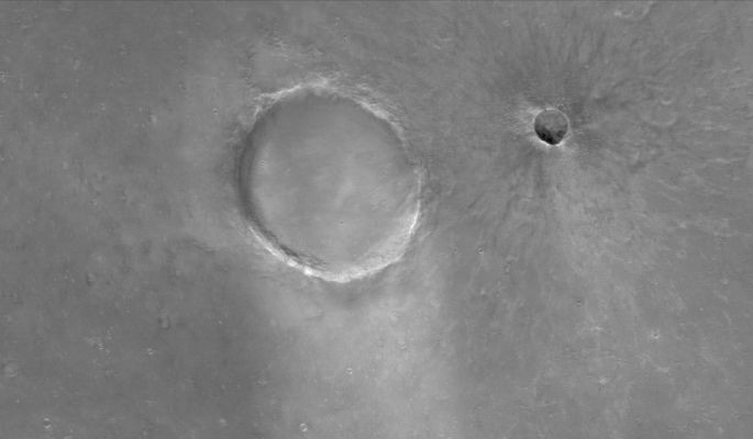 Unnamed Craters in Syrtis Major Planum (Original NASA/MGS/MSSS b/w Frame)
Caption NASA originale:"This MGS-MOC image shows a portion of Syrtis Major Planum, dominated in this area by two Impact Craters of differing age. The large one is about 1,3 Km (approx. 0,8 miles) in diameter, the smaller is about 250 mt (~820 feet) across. 
The smaller Unnamed Crater has a well-defined Ejecta Blanket and Rays emanate outward from its center. The larger Unnamed Crater does not exhibit these features. The larger one is older, and its Ejecta Blanket and Rays have been removed and degraded over time". 

Location near: 5,4° North; 294,2° West
Image width: ~3 Km (~1,9 mi)  
Illumination from: upper left  
Season: Northern Spring
Parole chiave: Mars from orbit - Craters - Unnamed Craters - Syrtis Major Region