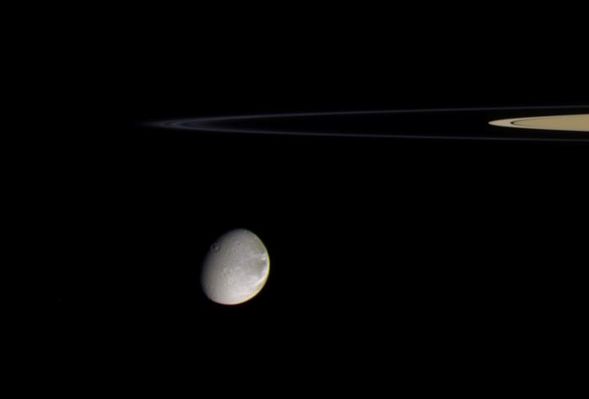 Dione and the F-Ring (in natural colors)
Original caption:"Saturn's moon Dione is about to swing around the edge of the thin F-Ring in this color view. More than one thin strand of the F-Ring's tight spiral can be seen here. 
The terrain seen on Dione is on the moon's Saturn-facing hemisphere.

Images taken using infrared, green and ultraviolet spectral filters were composited to create this color view. The images were taken with the Cassini spacecraft narrow-angle camera on Sept. 20, 2005, at a distance of approx. 2 MKM (about 1,2 MMs) from Dione and at a phase angle of 48°. 
The image scale is of about 12 Km (such as roughly 7 miles) per pixel".
Parole chiave: Saturn's Moons - Dione