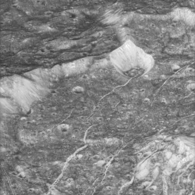 The surface of Dione from about 4486 Km
The terrain in this image is located within a 60-Km-wide impact crater along the feature called Padua Linea. The western rim of the encompassing crater runs from the middle left to the upper right. The crater's central peak can be seen at the lower right. Multiple generations of fractures are visible here. Numerous fine, roughly parallel linear grooves run across the terrain from top to bottom and are interrupted by the larger, irregular bright fractures. In several places, fractures postdate some deposits in the bottoms of craters that are not badly degraded by time. Such a fracture, for example, runs from the center toward the upper right. Most of the craters seen here have bright walls and dark deposits of material on their floors. As on other Saturnian moons, rockslides on Dione may reveal cleaner ice, while the darker materials accumulate in areas of lower topography and lower slope (e.g. crater floors and the bases of scarps). This view is centered on terrain near 11° South lat. and 238° West long.
Parole chiave: Saturn's Moons - Dione - Padua Linea