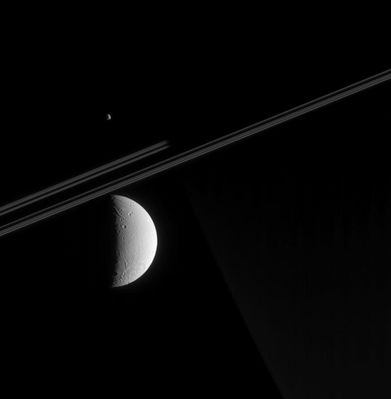 Dione and Epimetheus
Caption NASA originale:"Cassini looks toward Saturn's night side in this view, capturing a glimpse of Dione's tortured surface in the foreground and a far-off view of Epimetheus, beyond Saturn. The spacecraft was just 1/10th of a degree above the ring-plane when this image was taken. 
Parts of Dione's surface have been stretched and ripped apart by tectonic forces. Some of these faults are visible here, as is a large impact basin (not seen in NASA Voyager spacecraft images) near the moon's South Pole. Although this crater's diameter has not yet been measured by imaging scientists, it appears to be wider than 250 Km, which would make it the largest impact structure yet identified on this moon. 
The image was taken in visible light with the Cassini spacecraft narrow-angle camera on May 5, 2005, at a distance of approx. 910.000 Km from Dione; 1,28 MKM from Epimetheus and 1,42 MKM from Saturn. The image scale is 5 Km per pixel on Dione and 9 Km per pixel on Epimetheus".
Parole chiave: Saturn's Moons - Dione and Epimetheus