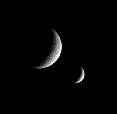 Brothers in the Night
The Cassini spacecraft captures this dual portrait of an apparently dead moon and one that is very much alive. Tethys, in the foreground, shows no signs of recent geologic activity. Enceladus, instead, is covered in fractures and faults - near its South Pole in particular - and spews icy particles into space from active vents. Tethys' giant crater Odysseus lurks in the dark just west of the terminator. North on the moons is up. 

The image was taken in visible light with the Cassini spacecraft narrow-angle camera on Nov. 29, 2005 at a distance of app.x 970.000 Km (roughly 600.000 miles) from Tethys and at a Sun-Tethys-spacecraft angle of 122°. Cassini was then 1,1 MKM (700.000 miles) from Enceladus. Image scale is about 6 Km per pixel on Tethys (at left) and 7 Km per pixel on Enceladus (at right).
Parole chiave: Saturn's Moons - Enceladus and Tethys