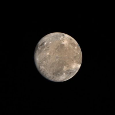 Ganymede from 2,6 MKM
This picture was taken on March 4, 1979 at 2:30 A.M. PST by Voyager 1 from a distance of about 2,6 MKM (such as about 1,6 MMs). Ganymede is Jupiter's largest satellite with a radius of about 2600 Km which means about 1,5 times that of our Moon. Ganymede has a bulk density of only approximately 2,0 g/cc (almost half that of the Moon). 
In the light of the above, Ganymede is probably composed of a mixture of rock and ice. The features here, the large dark regions, in the northeast quadrant, and the white spots, resemble features found on the Moon, mare and impact craters respectively. The long white filaments resemble rays associated with impacts on the lunar surface. The various colors of different regions probably represent differing surface materials. There are several dots on the picture of single color (blue, green, and orange) which are the result of markings on the camera used for pointing determinations and are not physical markings.
Parole chiave: Jupiter's moons - Ganymede
