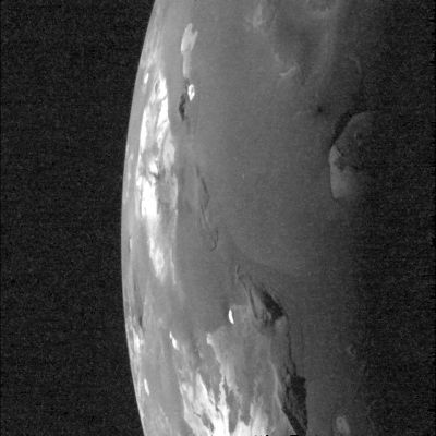 Io: the Loki Volcano from Galileo (RAW-HR and b/w Original NASA-Galileo Spacecraft Frame)
Caption NASA:"Light from the setting Sun falls across the Loki Volcanic Region on Jupiter's moon Io in this image taken by NASA's Galileo Spacecraft taken on October, 16, 2001.

The image was taken to examine the relative depths and heights of the major Surface Features existing in the Region. The Sun illuminates the surface from the right. Galileo's camera caught the large Volcanic Crater, or "Patera" of Loki near the Terminator (such as the boundary line between night and day). The image also shows several smaller craters plus shadows cast by the high peaks of several mountains.
Shadows cast by the low Sun should reveal any topography associated with Loki, such as a plateau in the center of the Patera or high Patera Walls. The near absence of shadows in this Region surprised Galileo scientists, as they had expected much more pronounced topography near Loki.
Another surprising aspect of this image is that features that have been black in previous Voyager and Galileo images of Loki, such as the dark Lava Flows visible inside the Patera, are here brighter than their surroundings. The best explanation is that the shiny, glassy surfaces of chilled Lava Flows look extremely dark when the Sun is directly overhead, but they reflect the Sun's light comparatively well when it shines at a low angle, in a similar manner to the reflective surfaces of bodies of water. 
Other Volcanic Paterae in this image show the same unusual reflectance as seen at Loki. Some of them are being viewed at such an angle that these reflections from Lava Flows are the brightest features in the image. This image tells us that Lava Flows on Io chill quickly and form glassy surfaces, not unlike recently cooled lava flows in Hawaii.
The image has a resolution of about 1,1 Km (approx. 0,7 miles) per picture element. North is to the top of the picture".
Parole chiave: Jupiter moons - Io