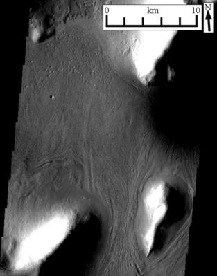 The Islands of Mars (Original NASA-2001 Mars Odyssey Orbiter b/w Frame)
New HR images of mid-latitude Mars are revealing glacier-formed landscapes far from the Martian Poles, says a leading Mars Researcher.
Conspicuous trains of debris in valleys, arcs of debris on steep slopes and other features far from the polar ice caps bear striking similarities to glacial landscapes of Earth, says Brown University's James Head III. When combined with the latest climate models and orbital calculation for Mars, the geological features make a compelling case for Mars having ongoing climate shifts that allow ice to leave the poles and accumulate at lower latitudes.
"The exciting thing is a real convergence of these things, said Head, who will present the latest Mars climate discoveries on Sunday, 16 October, at the Annual Meeting of the Geological Society of America in Salt Lake City (Utah). "For decades people have been saying that deposits at mid and equatorial latitudes look like they are ice-created, said Head. But without better images, elevation data and some way of explaining it, ice outside of Mars' polar regions was a hard sell.

Now high-resolution images from the Mars Odyssey spacecraft's Thermal Emission Imaging System combined with images from the Mars Global Surveyor spacecraft's Mars Orbiter Camera and Mars Orbiter Laser Altimeter can be compared directly with glacier features in mountain and polar regions of Earth. The likenesses are hard to ignore.

For instance, consider what Head calls "lineated valley fill." These are lines of debris on valley floors that run downhill and parallel to the valley walls, as if they mark some sort of past flow. The same sorts of lines of debris are seen in aerial images of Earth glaciers. The difference is that on Mars the water ice sublimes away (goes directly from solid ice to gas, without any liquid phase between) and leaves the debris lines intact. On Earth the lines of debris are usually washed away as a glacier melts.

Parole chiave: Mars from orbit - Unusual Mid-Latitudes Surface Features