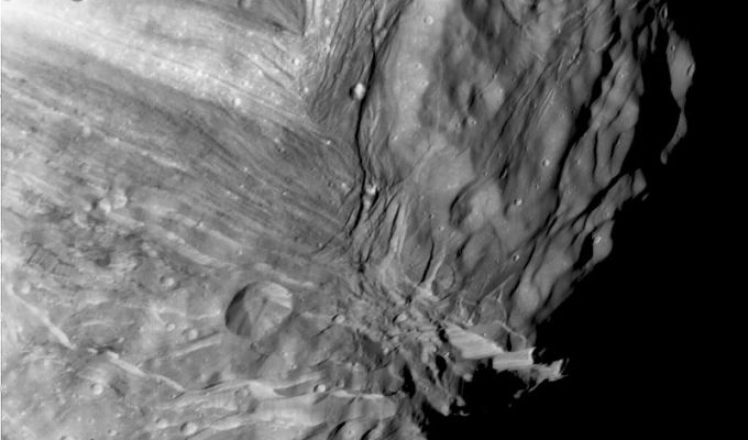 Miranda (close-up of the Verona Rupes Region) - HR
Caption NASA originale:"Miranda, innermost of Uranus' large satellites, is seen at close range in this Voyager 2 image, taken Jan. 24, 1986, as part of a HR mosaicing sequence. Voyager was some 36.000 Km (22.000 miles) away from Miranda. This clear-filter, narrow-angle image shows an area about 250 Km (150 mi) across, at a resolution of about 800 meters (2.600 feet). Two distinct terrain types are visible: a rugged, higher-elevation terrain (right) and a lower, striated terrain. Numerous craters on the rugged, higher terrain indicate that it is older than the lower terrain. Several scarps, probably faults, cut the different terrains. 
The impact crater in the lower part of this image is about 25 Km (15 mi) across".
Parole chiave: Uranus' Moons - Miranda