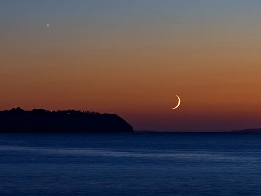 The Moon over St. Lawrence River
Da "NASA - Picture of the Day" del 9 Settembre 2005:"Shortly after sunset on September 6th, sky gazers around the world were treated to a lovely crescent Moon in western skies - joined by bright planets Venus and Jupiter. 
In this colorful telephoto view from near Quebec City, Canada, the Moon is nestled just above the wide St. Lawrence River. Lights on the horizon are along the river's southern shore. Also known as the evening star, Venus is at the upper left and Jupiter at the upper right, while another prominent celestial beacon, Spica, can be seen shining through the twilight below Venus. 
Spica, actually a very close pair of hot blue stars some 260 LY away, is the brightest star in the constellation Virgo".
Parole chiave: Artistic Pictures
