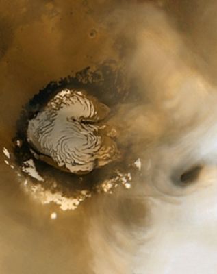 Annular Clouds over the North Pole (Natural Colors; credits: NASA/JPL/MSSS)
Caption NASA:"Two annular (---> somewhat circular) clouds are seen in the upper left corner of this mosaic of MOC wide angle camera daily global mapping images. To the right of the picture's center is the Martian North Polar Cap. The image has a scale of about 7,5 Km (about 4,7 miles) per pixel. Annular clouds are common in mid-Northern Summer in the North Polar Region and may result from eddy currents in the lower atmosphere. The appearance of such clouds happens every year; this year they came like clockwork within a two-week forecasted period, based on the previous 4 Martian Years of experience gained from MGS MOC daily global imaging. 

Despite their superficial resemblance to Earth-orbiting satellite views of hurricanes, these cloud features are not the result of strong winds and they typically dissipate later in the day. The pictures used to make this mosaic were acquired less than 2 days before the MOC was turned off for MGS's 5th Mars-Earth Solar Conjunction period. During Conjunction, Mars was on the other side of the Sun, relative to Earth, and thus MGS could not transmit data (through the Sun) during the second half of October".
Parole chiave: Mars from orbit - North Polar Cap