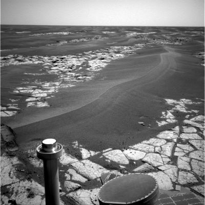 Meridiani's Side Winders - Sol 795
Caption NASA originale:"NASA's MER Opportunity continues to cut southward across a plain marked by large sand ripples and a pavement of outcrop rock. The ripple in the center of the image shows a distinct pattern of banding, which the science team hopes to investigate more closely during the trek through this terrain. 
The banding and other features have inspired a hypothesis that Meridiani ripples are old features that are currently being eroded, and not transported, by wind. 
This NavCam image was taken on Opportunity's Sol 795 (such as April 19, 2006".

Nota: e finalmente l'hanno detto! I Side-Winders, come ormai appariva ovvio (e come noi scriviamo da mesi), molto probabilmente NON sono disegnati dal vento, bensì - nel tempo - sono SCOLPITI (rectius: erosi) dal vento.
Si tratterebbe, quindi, di rilievi superficiali alquanto duri. Ma se ci pensate un momento, neppure questa spiegazione, in fondo, ci pare totalmente accettabile, ed il motivo è piuttosto evidente: se i Side-Winders fossero effettivamente dei rilievi di sabbia ultracompatta (e quindi simile ad una roccia, agevolmente scolpibile, ma pur sempre roccia), come spiegare le profonde tracce che il Rover si lascia alle spalle e che evidenziano una tessitura del suolo "resistente", ma ben lungi dall'essere definibile come di tipo "roccioso" (ancorchè friabile)? 
Pensateci: e se la sabbia (compatta) di Meridiani, fosse tale solo perchè impregnata di qualcosa (magari un'acqua ricchissima di sali, o magari degli idrocarburi)? Qualunque sia la verità, per ora ci accontentiamo di questa piccolissima (ma significativa) apertura della NASA: "forse - se abbiamo interpretato bene quello che scrivono - dovremo rivedere qualcuna delle nostre ipotesi di partenza; forse non tutto è come sembra".

Già.
Parole chiave: Martian Surface - Side-Winders