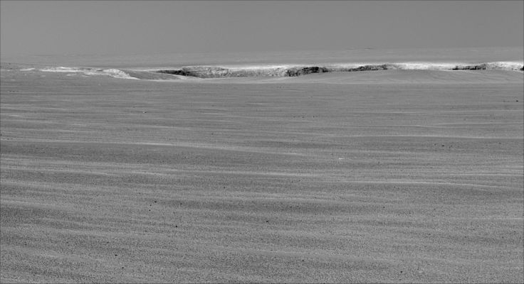Only 50 meters away... (1) - Sol 943
Caption NASA originale:"A drive of about 60 mt (approx. 200 feet) on the 943rd Sol, of Opportunity's exploration of Mars' Meridiani Planum Region (such as Sept. 18, 2006) brought the NASA Rover to within about 50 mt (approx. 160 feet) of the rim of Victoria Crater. 
This crater has been the mission's long-term destination for the past 21 Earth months. Opportunity reached a location from which the cameras on top of the Rover's mast could begin to see into the interior of Victoria. 
This frame was taken on Sol 943 by the PanCam and it shows the upper portion of interior crater walls facing toward Opportunity from up to about 850 mt (half a mile) away. The amount of vertical relief visible at the top of the interior walls from this angle is about 15 mt (roughly 50 feet). The exposure was taken through a PanCam filter selecting wavelengths centered on 750 nanometers". 
Parole chiave: Victoria Crater