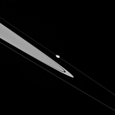 Pandora and the F-Ring
This dramatic image shows Saturn's craggy (---> rocciosa, colma di dirupi) moon Pandora skimming (to skim---> rasentare, sfiorare) along the F-Ring's outer edge. 
Pandora orbits about 1.000 Km (approx. 620 miles) exterior to the Ring, but, in this view, is projected onto the Ring. 
The moderately high-resolution of the image reveals the moonlet's odd shape.
The image was acquired from less than 1 degree below the Ring-Plane and taken in visible light with the Cassini spacecraft narrow-angle camera on Oct. 29, 2005, at a distance of approx. 455.000 Km (roughly 283.000 miles) from Pandora. The image scale is 3 Km (about 2 miles) per pixel.
Parole chiave: Saturn's Moons - Pandora