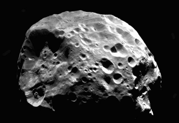 Phoebe (Original NASA/JPL/ASU b/w Image-Mosaic)
Was Saturn's moon Phoebe once a comet? Images from the Cassini spacecraft taken two years ago (early 2004) when entering the neighborhood of Saturn, indicate that Phoebe may have originated in the outer Solar System. 
Phoebe's irregular surface, retrograde orbit, unusually dark surface, assortment of large and small craters, and low average density appear consistent with the hypothesis that Phoebe was once part of the Kuiper Belt of icy comets beyond Neptune before being captured by Saturn. Visible in the above image of Phoebe are craters, streaks, and layered deposits of light and dark material. The image was taken from around 30.000 Km out from this 200-Km diameter moon. 

Two weeks after taking the above image, Cassini fired its engines to decelerate into orbit around Saturn. 
Parole chiave: Saturn's Moons - Phoebe