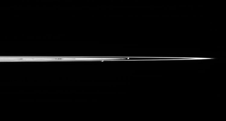Prometheus and Pandora
Saturn's moons Prometheus and Pandora are captured here in a single image taken from less than 1° above the dark side of Saturn's Rings. Pandora is on the right and Prometheus is on the left. Prometheus is 102 Km (63 miles) across, while Pandora is 84 Km (52 miles) across. 
The two moons are separated by about 69.000 Km (about 43.000 miles) in this view. The F-Ring, extending farthest to the right, contains a great deal of fine, icy material that is more the size of dust than the boulders thought to comprise the dense B-Ring. 
These tiny particles are particularly bright from this viewing geometry, especially at right near the ansa, or edge. 
At left of center, a couple of ringlets within the Encke gap (325 Km or 200 miles wide) can also be easily seen due to their fine dust-sized material. The other dark features in the Rings are density waves and bending waves. The image was taken in visible light from a mean distance of 1,85 MKM from the moons.
Parole chiave: Saturn's Moons - Prometheus and Pandora