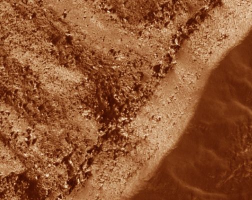 Gullied Trough in Noachis Terra (extra-detail mgnf - false colors)
The majority of the gullies on both sides of the trough appear to originate at a boulder-rich layer seen in this subimage. 
The layer appears dark on the sunlit slope because the boulders sticking out from the slopes cast shadows. If these gullies formed by water from the subsurface, then it is possible that this layer is a permeable layer that conducted water to the surface. 
The layer is deteriorating and traveling down slope in the form of boulders. 
These boulders can clearly be seen in the alcoves of the gullies on both sides of the trough.

Note that the alternating stripes on the lower right (Dx) side of the image are an artifact from camera noise. They are not real features.
Parole chiave: Mars from orbit - Trough with gullies