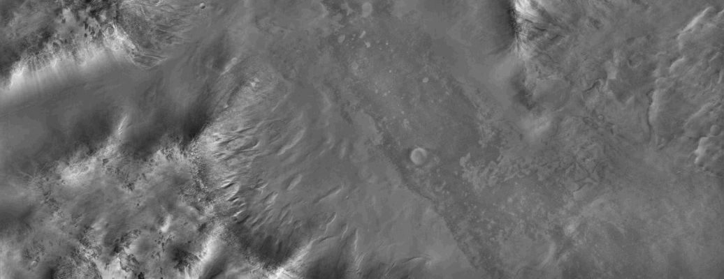 Argyre Basin, in the morning twilights...
This image shows part of a low mountain belt that rings the Argyre Impact Basin in Mars' Southern Hemisphere. The mountains or hills seen here are located in the northwestern part of the Charitum Montes. Taken just minutes after the Sun had risen over the horizon, only the sun-facing slopes are well illuminated and much of the scene is in shadow, but the camera has nevertheless captured many details of the surface that are only dimly illuminated. There are terrains that are both smooth and rough at this scale (2,94 mt - or 9,65 feet per pixel). The rough terrain is littered with blocks roughly 10 mt (30 feet) across and the smooth material has a uniform appearance broken by subtle, undulating ridges. The rough terrains usually occur at relatively high elevations and smooth material occupies the lowest areas. In some locations it is evident that boulders from the rough terrain have tumbled downhill onto the smooth material. The smooth material is younger than the rough terrain, and some of it may have formed when water-rich or ice-rich debris flooded low-lying areas. In other areas the smooth material mantles the topography like deposits of airborne dust. Further upslope, the mountain flanks have a variety of rough textures. In places the terrain has been eroded into streamlined forms and striations, suggestive of glacial erosion. Gullies formed in one spot near bottom center. Perhaps the most striking aspect of this image is the dearth of fresh impact craters. The Argyre basin is thought to be billions of years old, but much more recent processes have greatly modified the surface. 

This image was taken by the High Resolution Imaging Science Experiment (HiRISE) camera onboard NASA's Mars Reconnaissance Orbiter spacecraft on March 24, 2006. The image is centered at 52.20 degrees south latitude, 300.75 degrees east longitude. It is oriented such that north is 7 degrees to the left of up. The range to the target was 1,470 kilometers (913 miles). With 2x2 pixel binning, the scale of the image is 2.94 meters (9.65 feet) per pixel, so objects as small as 8.82 meters (28.94 feet) are resolved. In total this image is 29.47 kilometers (18.31 miles) or 10,040 pixels wide and 76.44 kilometers (47.50 miles) or 26,011 pixels long. The image was taken at a local Mars time of 07:24 and the scene is illuminated from the upper right with a solar incidence angle of 87.1 degrees, thus the sun was about 2.9 degrees above the horizon. At an Ls of 29 degrees (with Ls an indicator of Mars' position in its orbit around the sun), the season on Mars is southern autumn.

Parole chiave: Mars from orbit - Argyre Basin