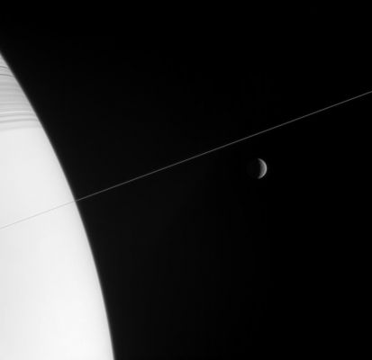 Crescent Rhea
Caption NASA originale:"Shadow-striped Saturn and its exquisitely thin Rings occupy the near-field view in this Cassini image, while a crescent moon Rhea hangs in the distance. 

A couple of bright pixels at the center of the image mark the location of the tiny moon Pan (only 26 Km, or 16 miles across). 

The image was taken in visible light with the Cassini spacecraft narrow-angle camera on Feb. 3, 2006, at a distance of approx. 4,1 MKM (2,5 MMs) from Saturn and 4,6 MKM (2,9 MMs) from Rhea. The image scale is 28 Km (approx. 17 miles) per pixel on Rhea".
Parole chiave: Saturn's Moons - Rhea