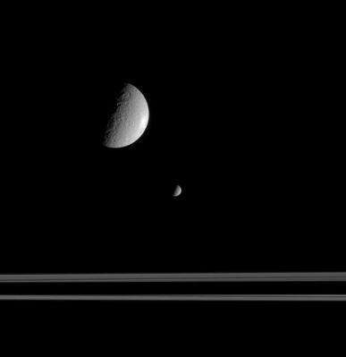 Mimas, Rhea and the Rings
Original caption:"The Saturn moon Mimas is much smaller than Rhea, but the geometry of this scene exaggerates the actual differences in size. Here, Mimas is on the opposite side of the rings from Rhea and Cassini. Saturn's shadow slices across the Ring-plane here. 
The view looks toward the Saturn-facing hemisphere on Mimas and the anti-Saturn hemisphere on Rhea. 

The image was taken in visible light with the narrow-angle camera on Sept. 9, 2005, from a distance of approx. 1,5 MKM (about 900.000 miles) from Rhea. Mimas was located on the far side of the Rings, such as about 670.000 Km (approx. 420.000 miles) farther from Cassini. The image scale is roughly 9 Km (about 6 miles) per pixel on Rhea and 13 Km (about 8 miles) per pixel on Mimas".
Parole chiave: Saturn's Moons - Mimas and Rhea