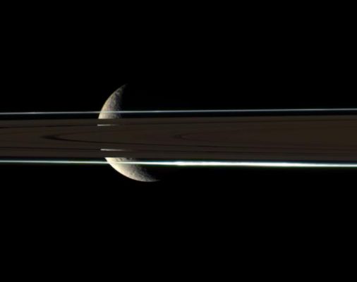 Rhea behind the Rings (natural colors)
Caption NASA originale:"The Rings cannot hide the ragged, icy crescent of Rhea, here imaged in color by the Cassini spacecraft: The second-largest moon of Saturn shines brightly through gaps in the Rings. 
Rhea lies beyond the dim, unlit side of the Rings. A diffuse clump of material lies in the F-Ring, on the side nearest to Cassini. 

Images taken using red, green and blue spectral filters were combined to create this natural color view, which approximates the scene as it might appear to human eyes. The view was acquired with the Cassini spacecraft narrow-angle camera on July 1, 2006 at a distance of approx. 1,2 MKM (about 700.000 miles) from Rhea and at a Sun-Rhea-spacecraft, or phase, angle of 118°. Image scale is roughly 7 Km (about 4 miles) per pixel".
Parole chiave: Saturn's Moons - Rhea