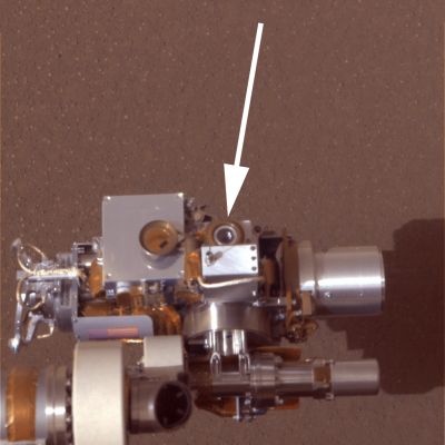 The "Microscopic Imager" - Sol 9 (Approximate True Colors; credits: NASA/JPL-Caltech)
Caption NASA originale:"The Microscopic Imager (circular device in center) is in clear view above the surface at Meridiani Planum, Mars, in this approximate true-color image taken by the panoramic camera on the Mars Exploration Rover Opportunity. The image was taken on the 9th Sol of the Rover's journey. 
The microscopic imager is located on the Rover's instrument deployment device, or arm. The arrow is pointing to the lens of the instrument. Note the dust cover, which flips out to the left of the lens, is open. This approximated color image was created using the camera's violet and infrared filters as blue and red".
Parole chiave: Microscopic Imager