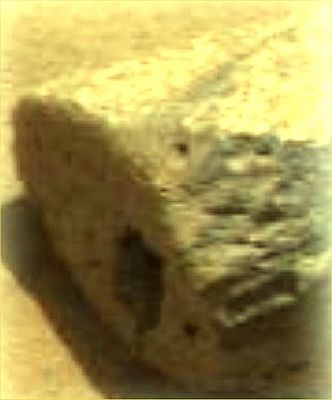 "Slot Rock" - Sol 14 (Natural Colors; credits : NASA/JPL)
Accanto alla conchiglia (se conchiglia è) che abbiamo battezzato "Ginny", c'è anche questa roccia che presenta un foro dalla forma squadrata sul suo lato corto. Che dire? In questo ingrandimento a falsi colori (abbiamo schiarito il frame per evidenziare la Singolarità) si vede, effettivamente, una sorta di buco la cui forma è - vagamente - rettangolare. I Cultori dei Martian Artifacts (Steve Troy su tutti) hanno visto in questo dettaglio un evidente segno di opera "intelligente" (umana o non umana, poi, rimane da chiarire). Noi, parafrasando quanto espresso da un Lettore, riteniamo questa Singolarità effettivamente meritevole di attenzione, ma non ci sentiamo, ogni qual volta vediamo un buco apparentemente sagomato o una pietra più liscia (o più squadrata) delle altre, di gridare "ecco un manufatto!". 
In realtà, secondo noi, in e da frames come questo, l'unica cosa che si può - logicamente e razionalmente - dire, è che siamo davanti ad una roccia la quale presenta un foro sulla sua superficie. Nulla di più.
Parole chiave: Controversial frame