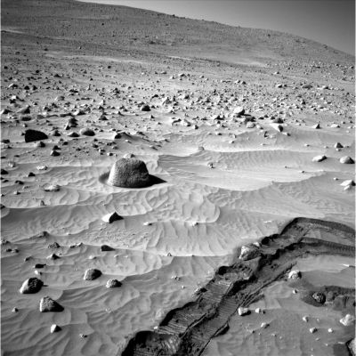 A lonely boulder and deep tracks (1)
Questo frame, ripreso durante il Sol 337 di Spirit, ci mostra, oltre alle (consuete) profondissime tracce lasciate dal Rover sulle sabbie di Gusaev Carter, anche un macigno solitario il quale sembra poggiare all'interno di una piccola fossa, fatta a forma di cerchio. Osservate attentamente, dunque, l'avvallamento su cui si trova il macigno in questione: sul suo lato in luce (a sinistra dell'Osservatore) dovreste chiaramente vedere una porzione di terreno liscia e rotondeggiante, leggermente più scura rispetto al resto del paesaggio. E' sufficiente un modesto ingrandimento dell'immagine per rendersi conto che quest'area liscia circonda tutta la roccia, formando una circonferenza (almeno per quanto attiene il versante a noi visibile). Si tratta, certamente, della conseguenza di un evento naturale, ma ciò non toglie che ci troviamo davanti ad una conformazione del suolo Marziano davvero strana. Forse l'effetto di qualche dust-devil di modestissime dimensioni? O magari un semplice mulinello d'aria?
Parole chiave: Mars rocks, sand and debris