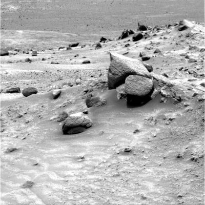 D�j� vu: this is the same 'coated rock' of Sol 485!
Allora la nostra sensazione, a dispetto dei circa 36 metri percorsi da Spirit negli ultimi 28 Soles, era esatta ed eccone la prova: la roccia che vedete ad un paio di metri - circa - più in basso rispetto ai 2 macigni (uno piatto e apparentemente appuntito ed un altro liscio) che dominano l'immagine nel suo lato Dx è la stessa 'coated rock' che avevamo visto ed isolato in un frame del Sol 485.
Abbiamo, ovviamente, letto tutti i Soles Summaries che il Centro Controllo Missione emette ogni 4/5 giorni (alle volte anche a distanze di tempo maggiori) e la nostra impressione era che Spirit, dopo aver ripercorso all'indietro qualche metro, avesse ripreso la marcia verso la sommità di Husband Hill.
Ovviamente ci siamo sbagliati, dato che il nostro Amico Rover, in realtà, è solo andato avanti ed indietro per un mese, fotografando sempre la stessa zona e sempre gli stessi sassi, sia pure da angoli visuali appena differenti.
Colpa solo nostra o forse anche il Centro Controllo Missione, a volte, fa un pò confusione?

Parole chiave: Mars rocks, sand and debris - Controversial image