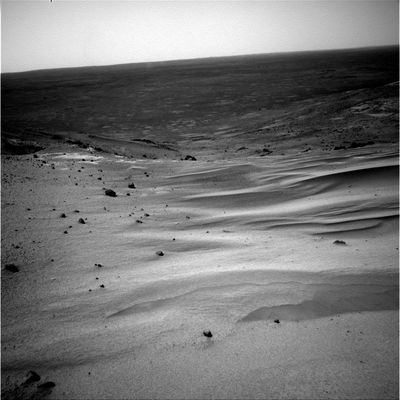 Beautiful Panorama: sand-dunes, boulders and far distant horizon (1) - Sol 605
Una meravigliosa "cartolina" ci mostra una serie di dune le quali, una dopo l'altra, paiono formare una sorta di "scivolo naturale" verso le pendici di Husband Hill (certo che sarebbe una via rapida e suggestiva per scendere ma, in tutta onestà, non ci sentiamo di suggerirla al nostro Amico Rover...). A parte qualche roccia sparsa nelle immediate vicinanze del Rover possiamo anche vedere, in lontananza, almeno due DD che si sollevano formando una sorta di coppia di colonne chiare che si stagliano piuttosto bene sullo sfondo (l'orizzonte lontano) più scuro.
Una bella immagine dalla definizione eccellente.
Parole chiave: Mars Panorama - Postcards from Mars
