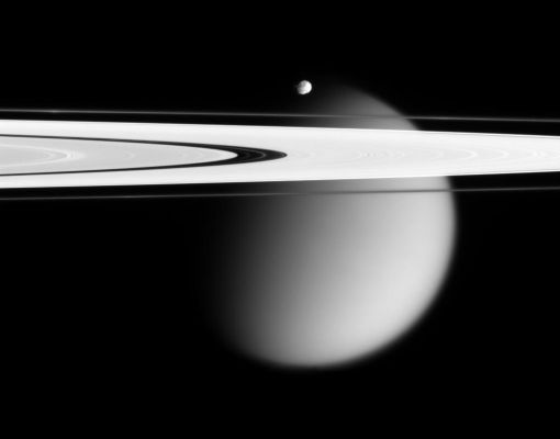 So close and yet so far...
The Cassini spacecraft delivers this stunning vista showing small, battered Epimetheus and smog-enshrouded Titan, with Saturn's A and F Rings stretching across the scene. The prominent dark region visible in the A-Ring is the Encke Gap, in which the moon Pan and several narrow ringlets reside. Moon-driven features that mark the A-Ring are easily seen to the left and right of the Encke Gap. The Encke Gap is about 325 Km (approx. 200 miles) wide. Pan is approx. 26 Km (about 16 miles) across. In an optical illusion, the narrow F-Ring, outside the A-Ring, appears to fade across the disk of Titan. A couple of bright clumps can be seen in the F-Ring. Epimetheus is approx. 116 Km (about 72 miles) across and giant Titan is roughly 5.150 Km (about 3.200 miles) across. 
The image was taken in visible light with the Cassini spacecraft narrow-angle camera on April 28, 2006, at a distance of approx. 667.000 Km(about 415.000 miles) from Epimetheus and 1,8 MKM (about 1,1 MMs) from Titan. The image captures the illuminated side of the rings. The image scale is 4 kilometers (2 miles) per pixel on Epimetheus and 11 kilometers (7 miles) per pixel on Titan.
Parole chiave: Saturn and Companions